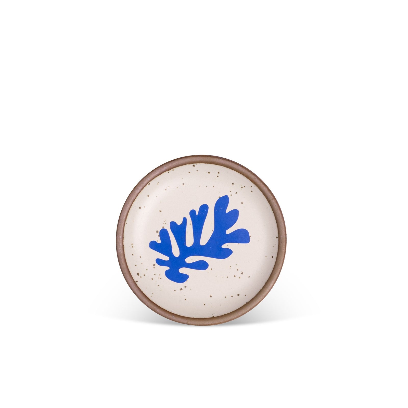 A round ceramic plate with a speckled off-white glaze, featuring a bold blue abstract shape in the center, against a plain white background.