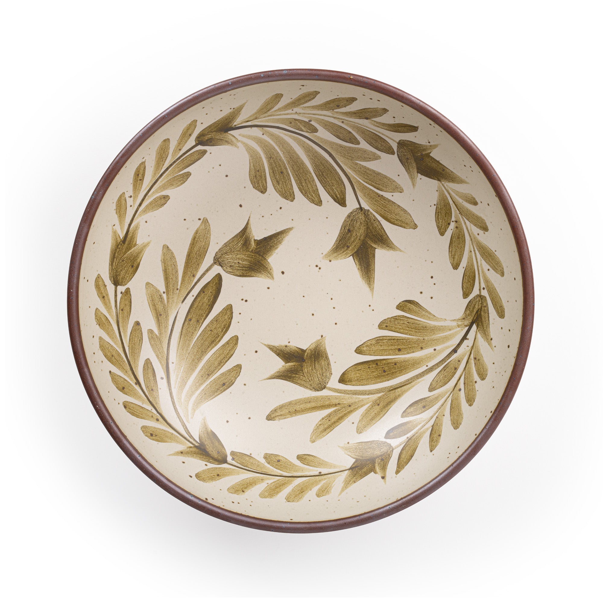 An overhead view of a large shallow serving ceramic bowl in a warm, tan-toned, off-white color featuring iron speckles and an unglazed rim, with handpainted greenery in an olive green color inside the bowl.