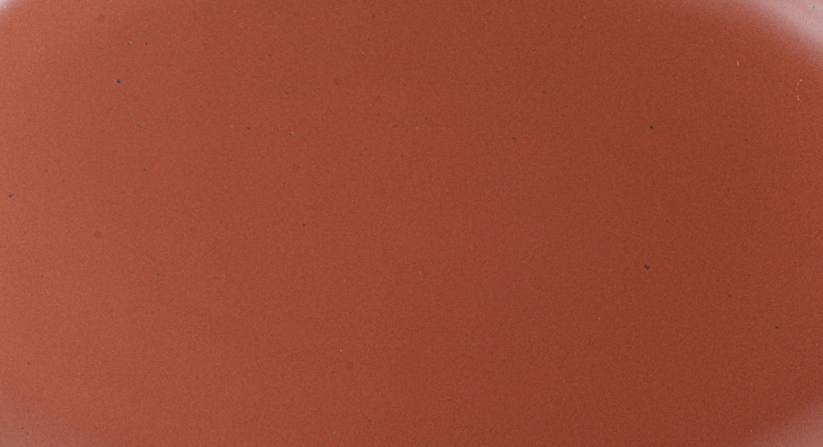 Closeup of a ceramic plate in a cool terracotta color with iron speckles.
