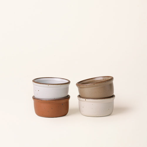 4 Small ceramic ramekins in an off-white, cool terracotta, cool white, and warm pale brown color with an unglazed rim.