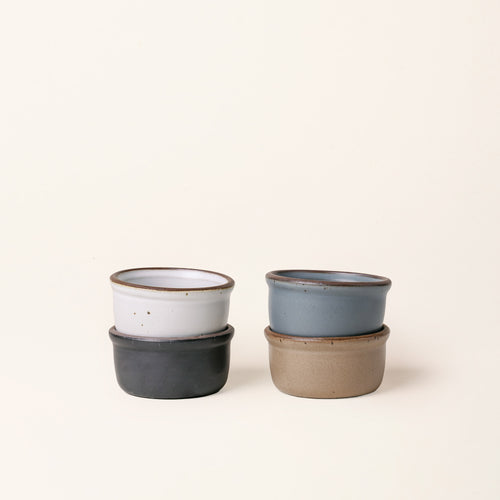 4 small ceramic ramekins in a graphite black, blue-grey, cool white, and warm pale brown color with an unglazed rim.