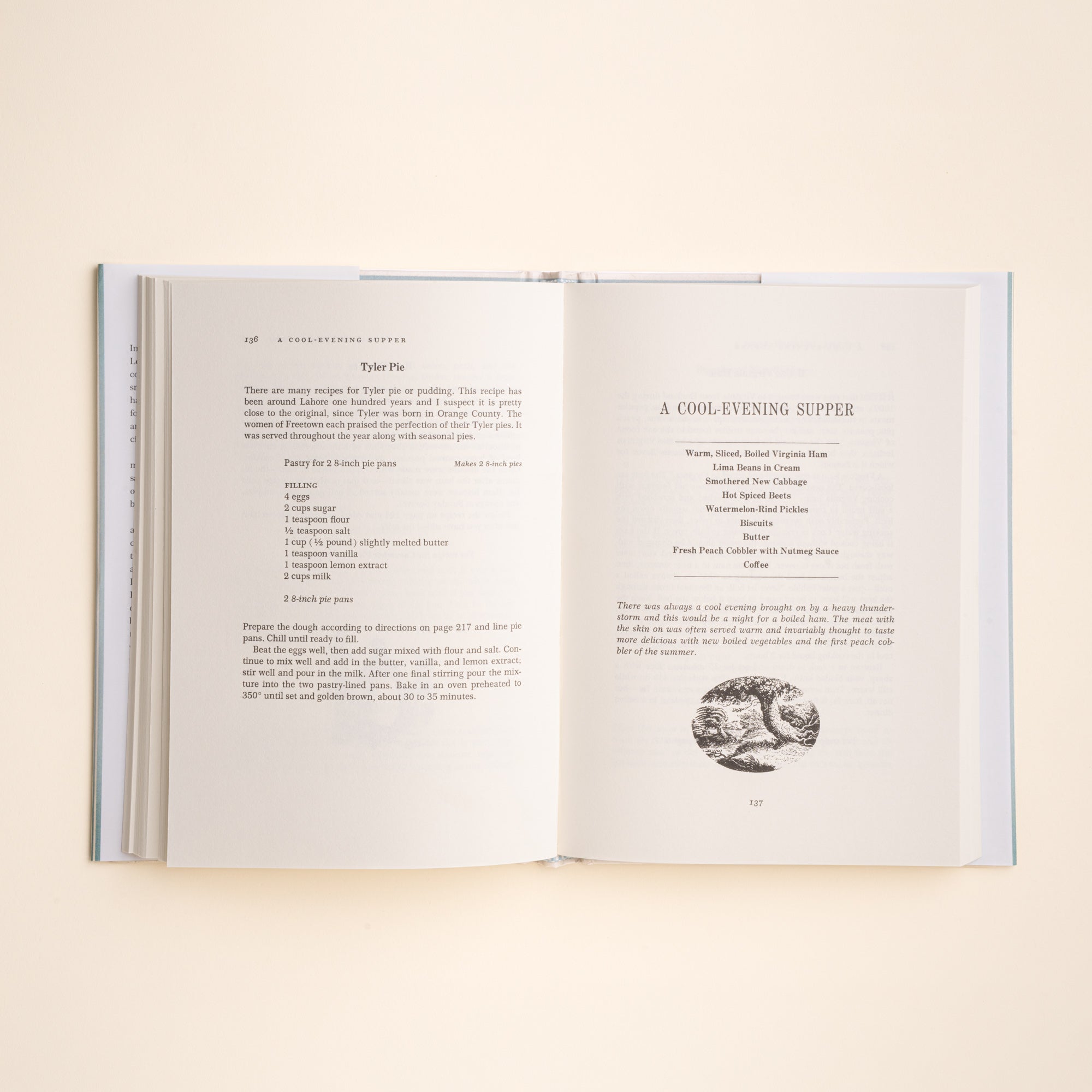 An open book laid flat on a light beige background, showing two printed recipe pages with text and a small black-and-white illustration.