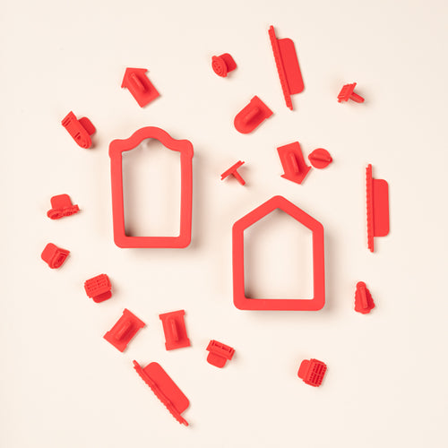 Red silicone cookie stamps and two house-shaped cookie cutters arranged on a cream background.