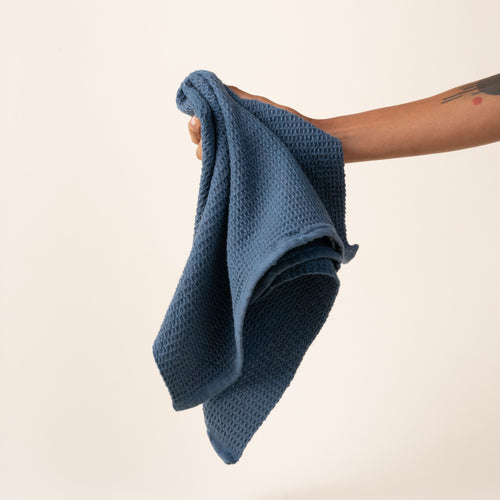 Hand holding a blue waffle weave kitchen towel