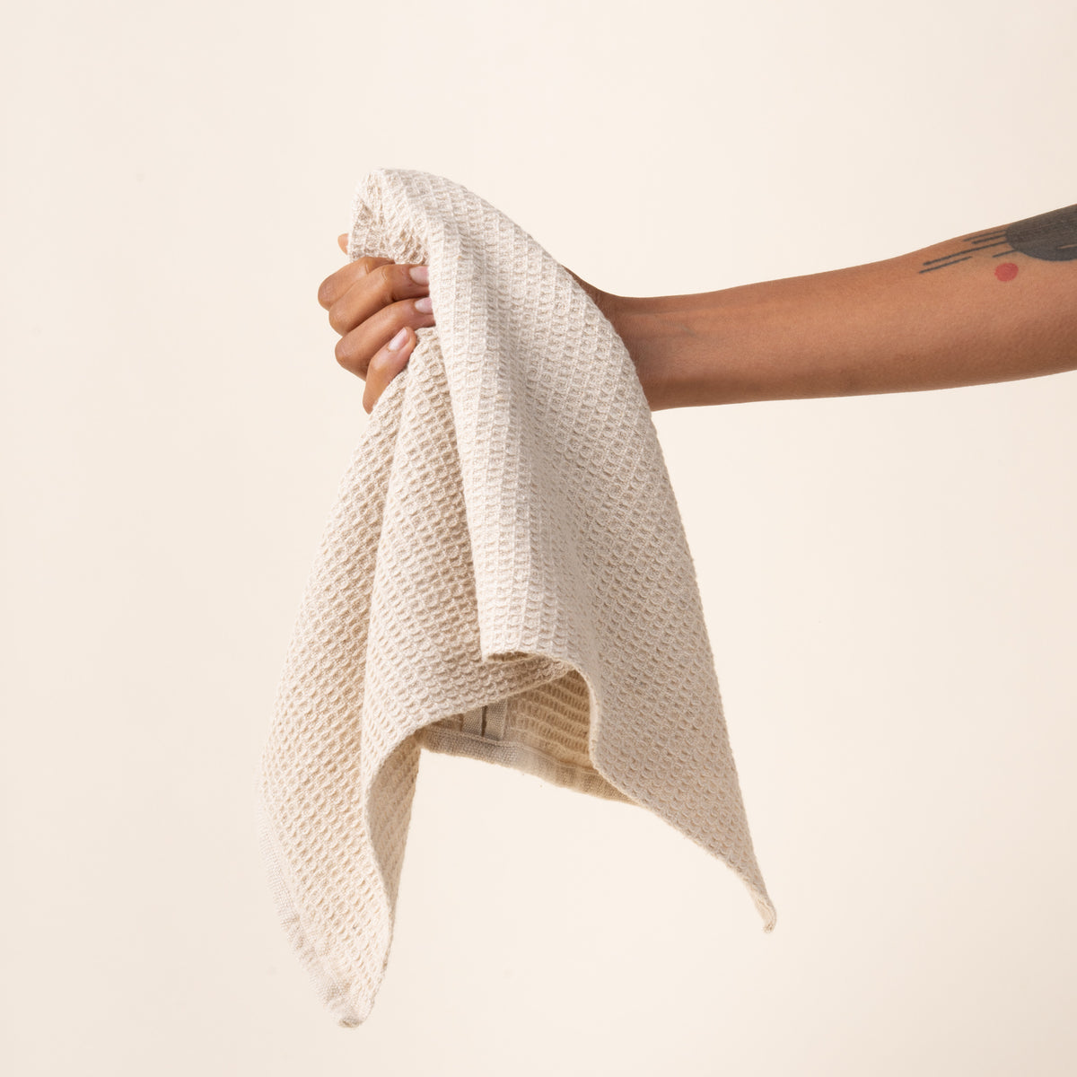 Hand holding a natural waffle weave kitchen towel