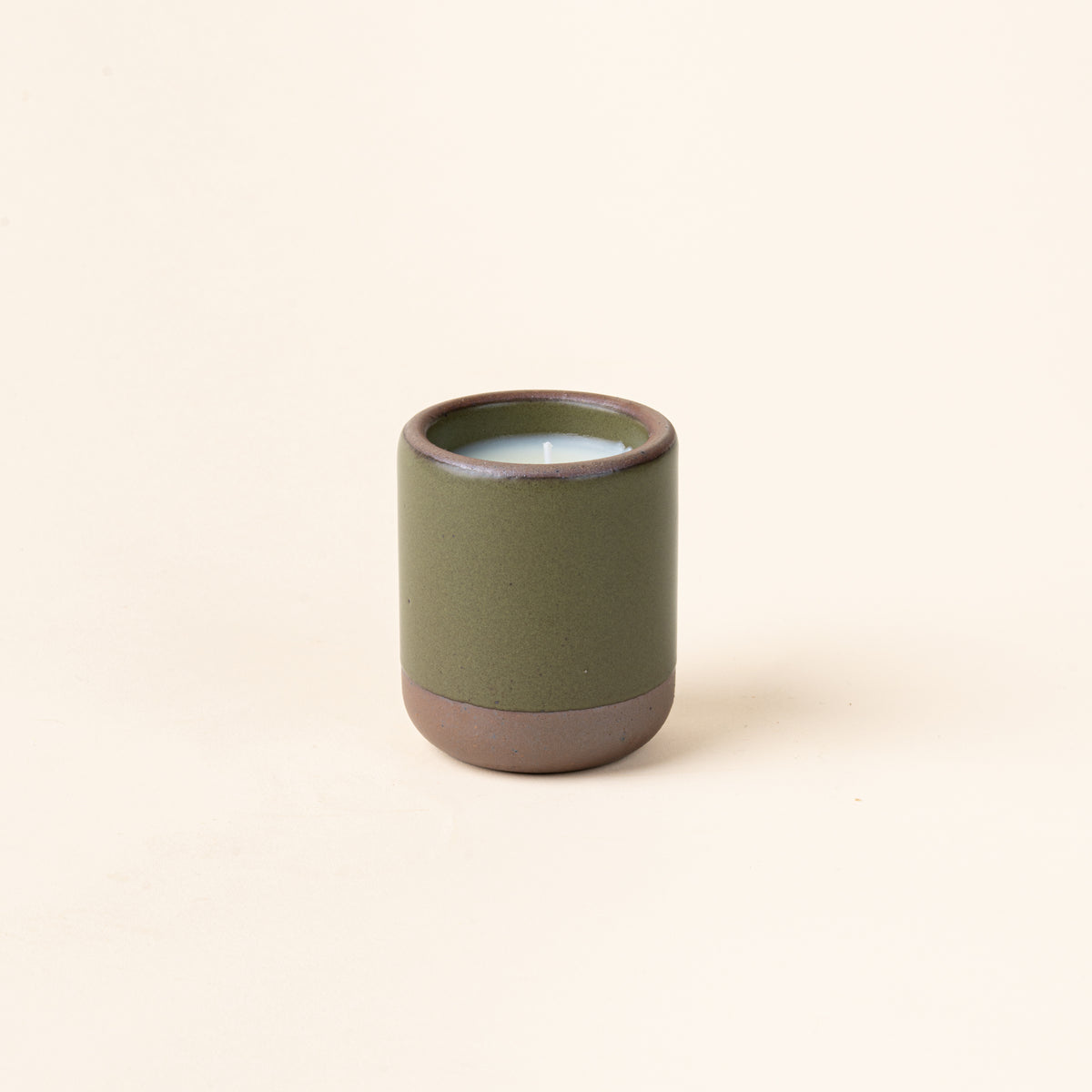 Small ceramic vessel in an olive green color with candle inside.