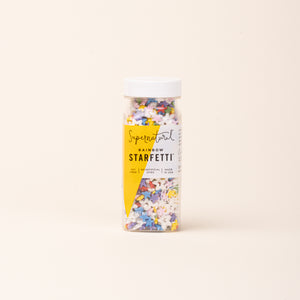 Bottle of colorful star-shaped sprinkles on a light background.