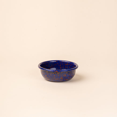 A small enamel bowl in midnight blue color with red splatter pattern.