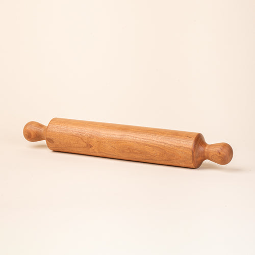 A simple dowel wooden rolling pin with rounded handles, in cherry.