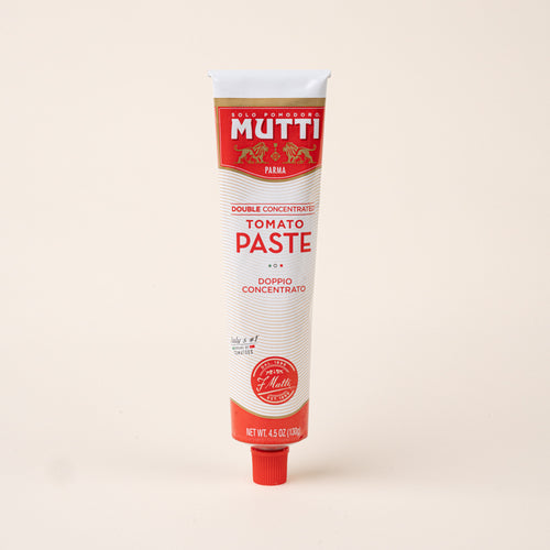 Tube of Mutti double concentrated tomato paste with red and white packaging and a red screw cap on a cream background.