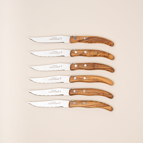 Set of six steak knives with polished steel blades and richly grained olive wood handles.
