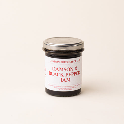 A glass jar with a white label of 'Damson & Black Pepper Jam'
