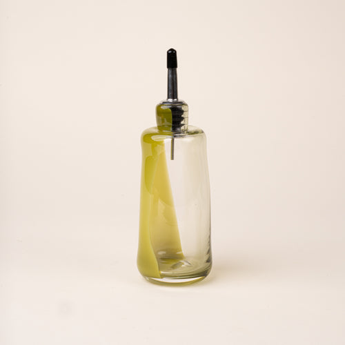 An olive-green glass oil or vinegar dispenser with a polished metal pour spout and black stopper.