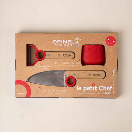 Opinel packaging box of Kitchen tool set for children with a peeler, chef’s knife, and red scraper, each with red accents.
