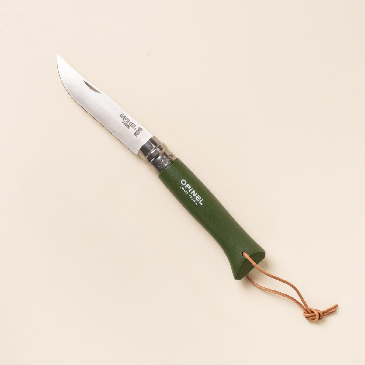 Green-handled folding knife with stainless steel blade and leather lanyard, shown on a neutral background.