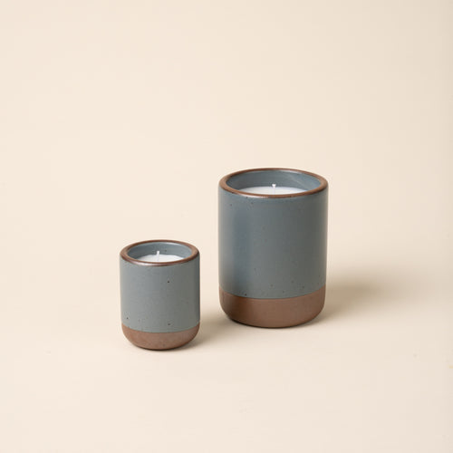 Small and large ceramic vessels in a blue-grey color with candle inside.