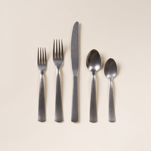 Five matte stainless steel utensils—salad fork, dinner fork, knife, tablespoon, and teaspoon—arranged on a neutral background.
