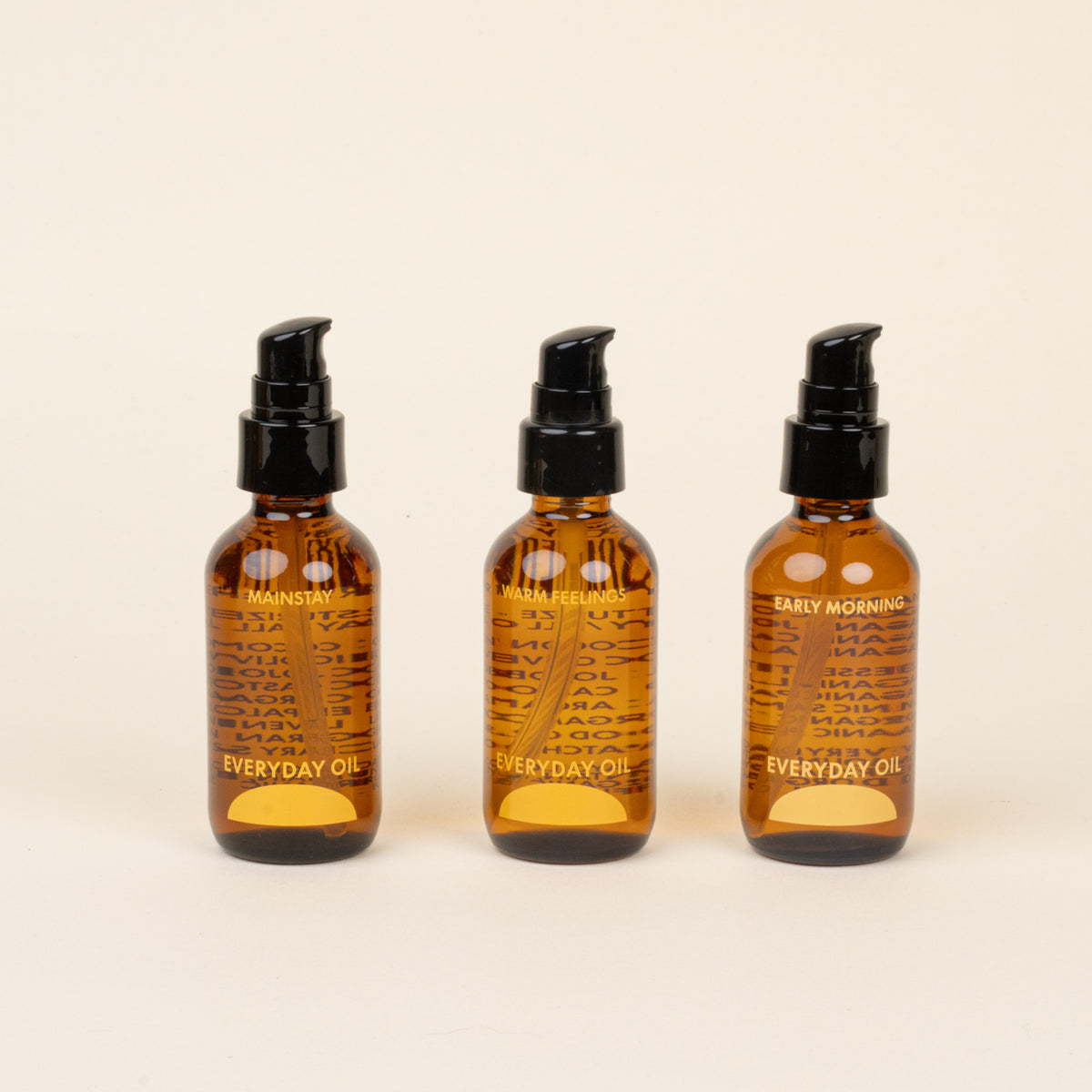 Three bottles of 'Everyday Oil' on a beige background