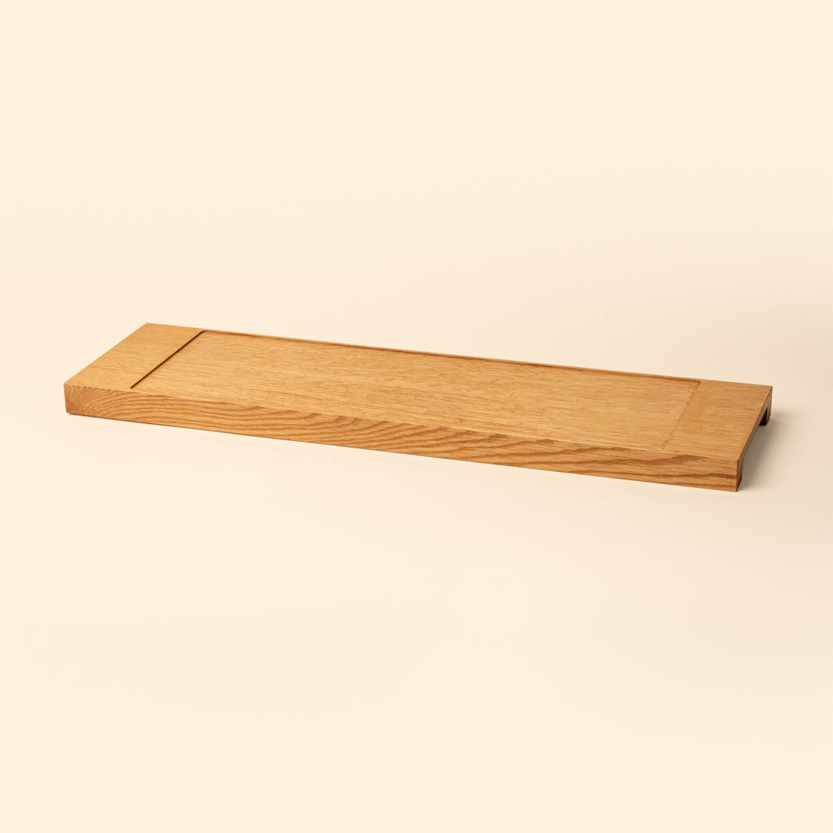 A narrow rectangle of light oak wood with a vertical groove at either end