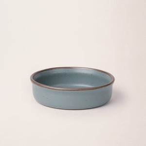 Wide shallow ceramic ramekin in a blue-grey color with an unglazed rim