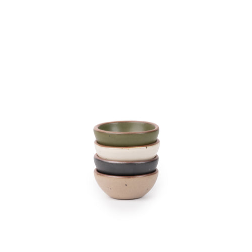 A stack of 4 tiny rounded ceramic bowls in an olive green, graphite black, off-white, and warm pale brown colors featuring iron speckles and an unglazed rim