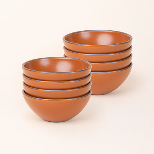 2 stacks of 4 medium rounded ceramic bowls in an earthy orange color featuring iron speckles and an unglazed rim
