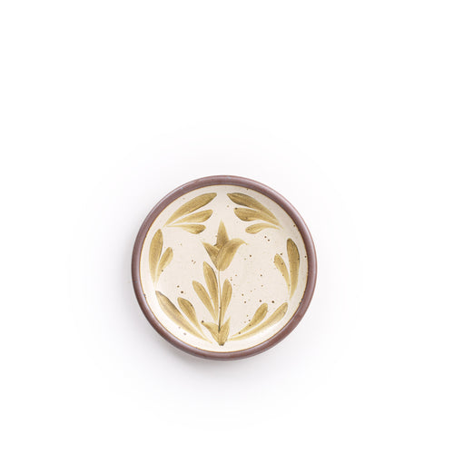 Small round ceramic plate with a hand-painted olive green flower and leaf design on a cream background with an exposed clay rim.