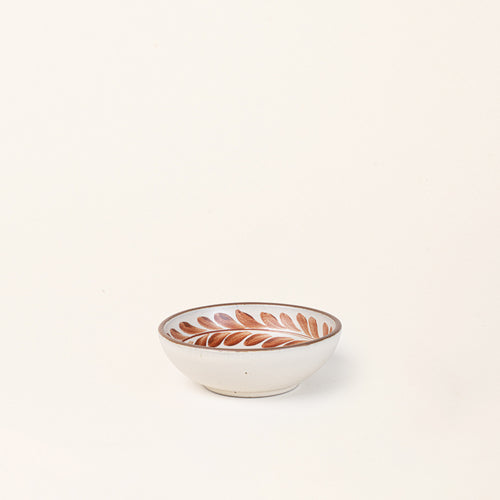 Small ceramic shallow bowl with a hand-painted cool terracotta leaf border on a cream interior and speckled cream exterior with an exposed clay rim.