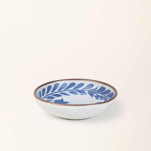 Medium ceramic shallow bowl with a hand-painted blue leaf border on a white interior and exterior with an exposed clay rim.