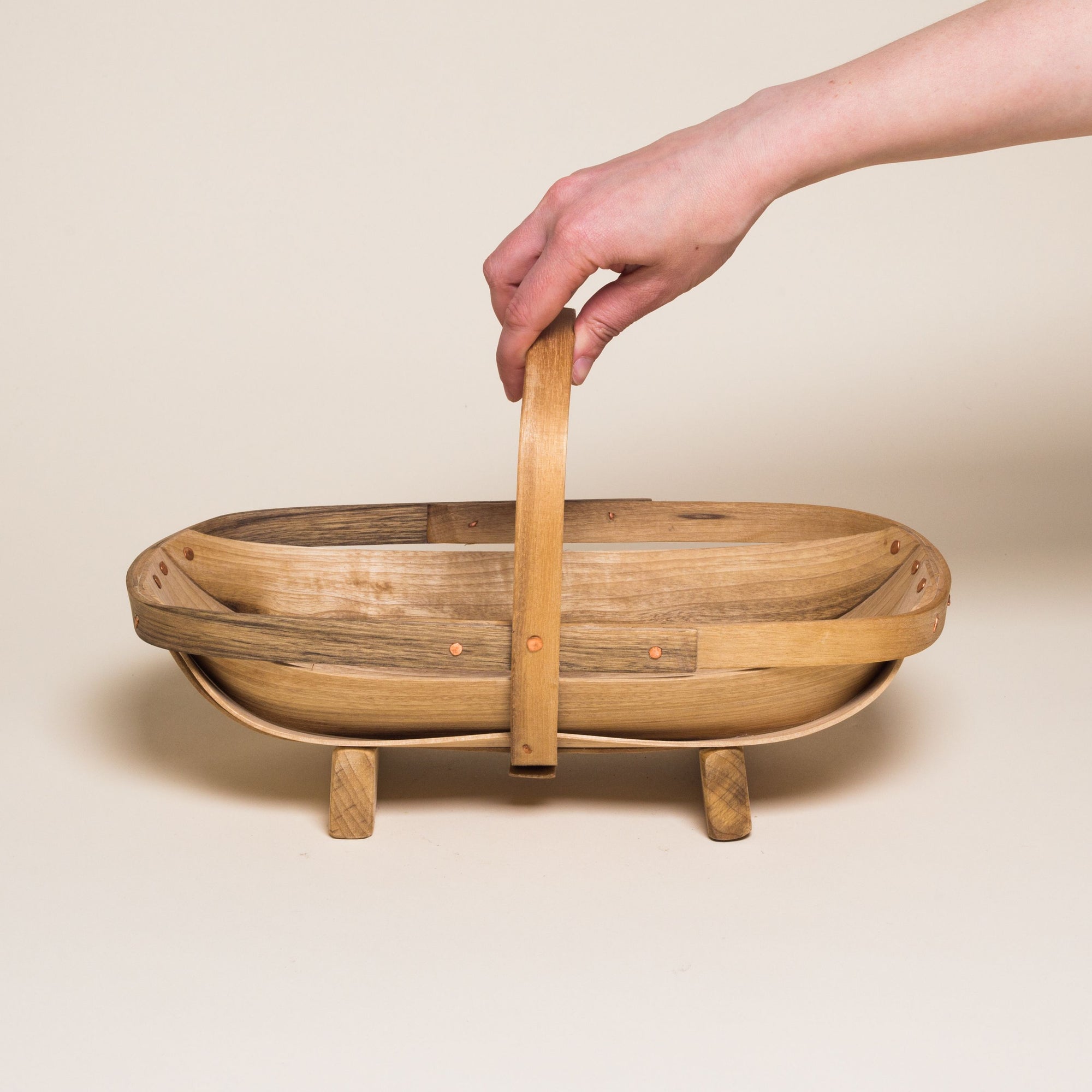 A hand reaches for a large myrtlewood trug for harvesting