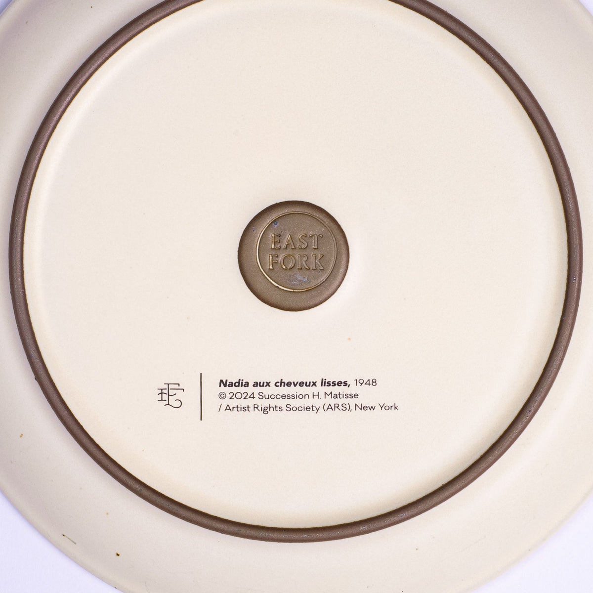 The back of a side plate with an East Fork stamp with a small decal of information about the artwork, Nadia aux cheveux lisses, by Henri Matisse.