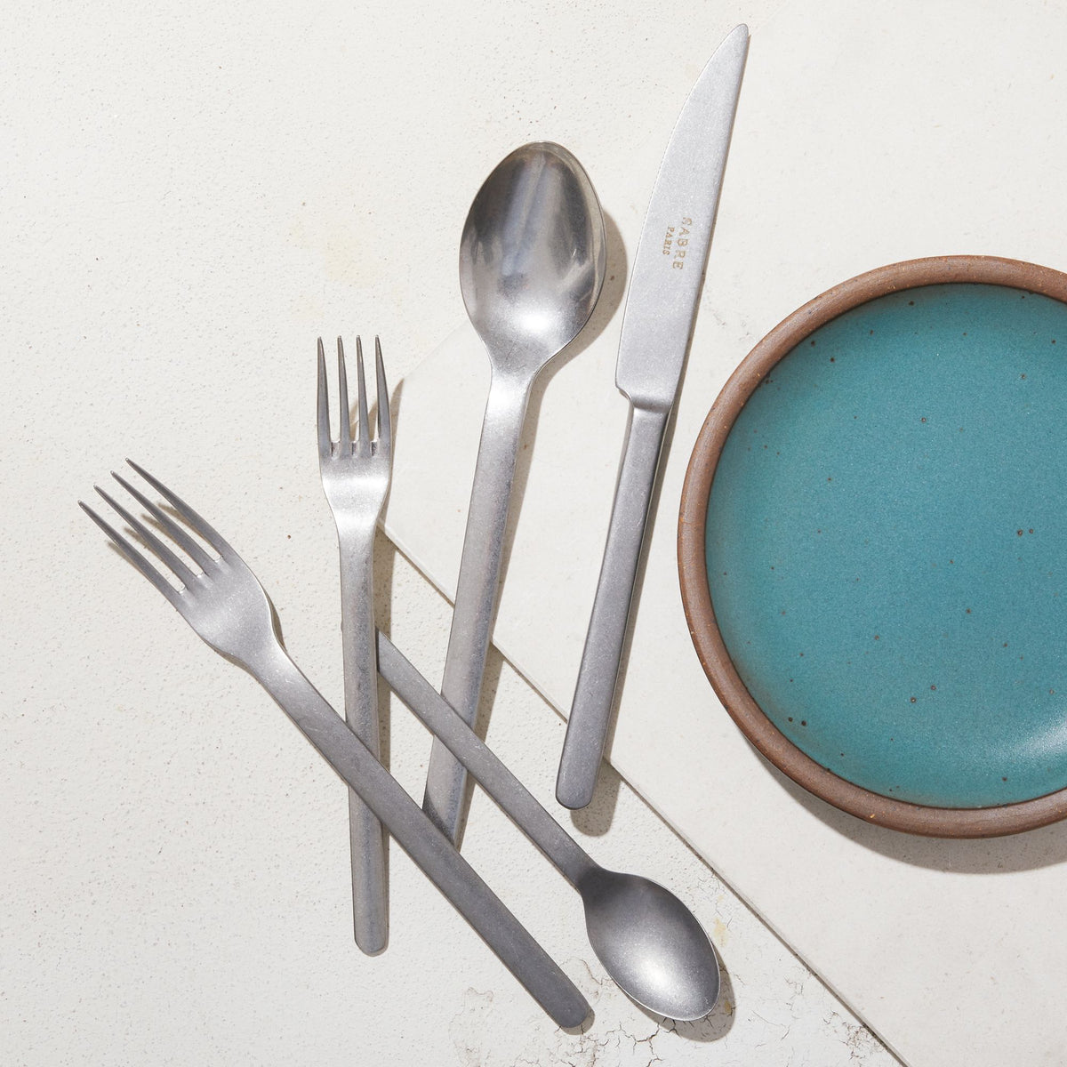 Stainless steel flatware next to Secret Beach plate