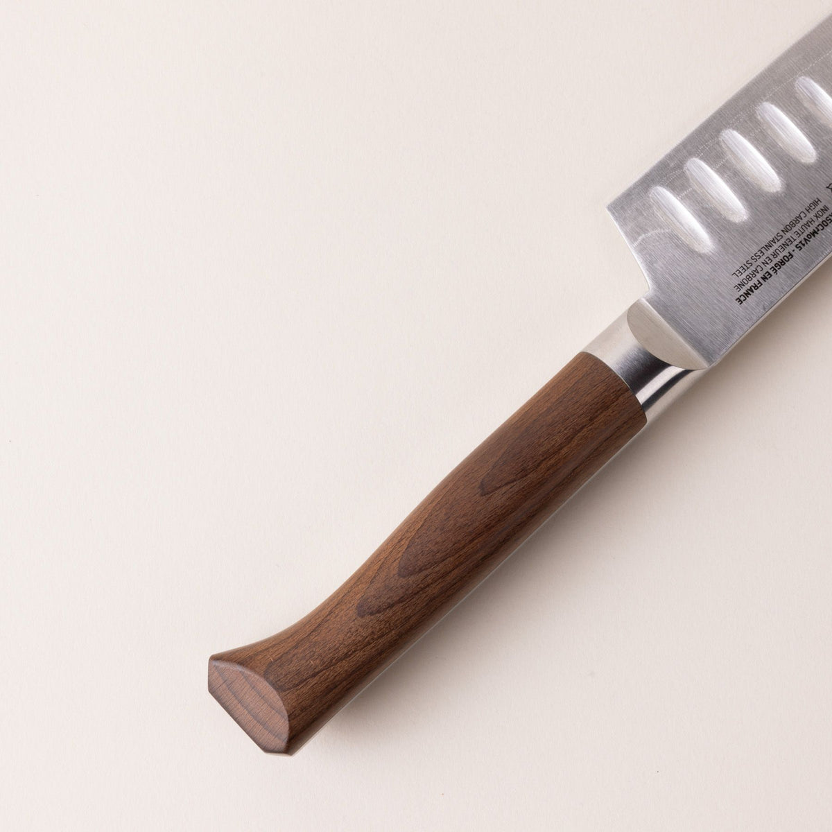 A close up of a beveled wooden handle on a santoku knife