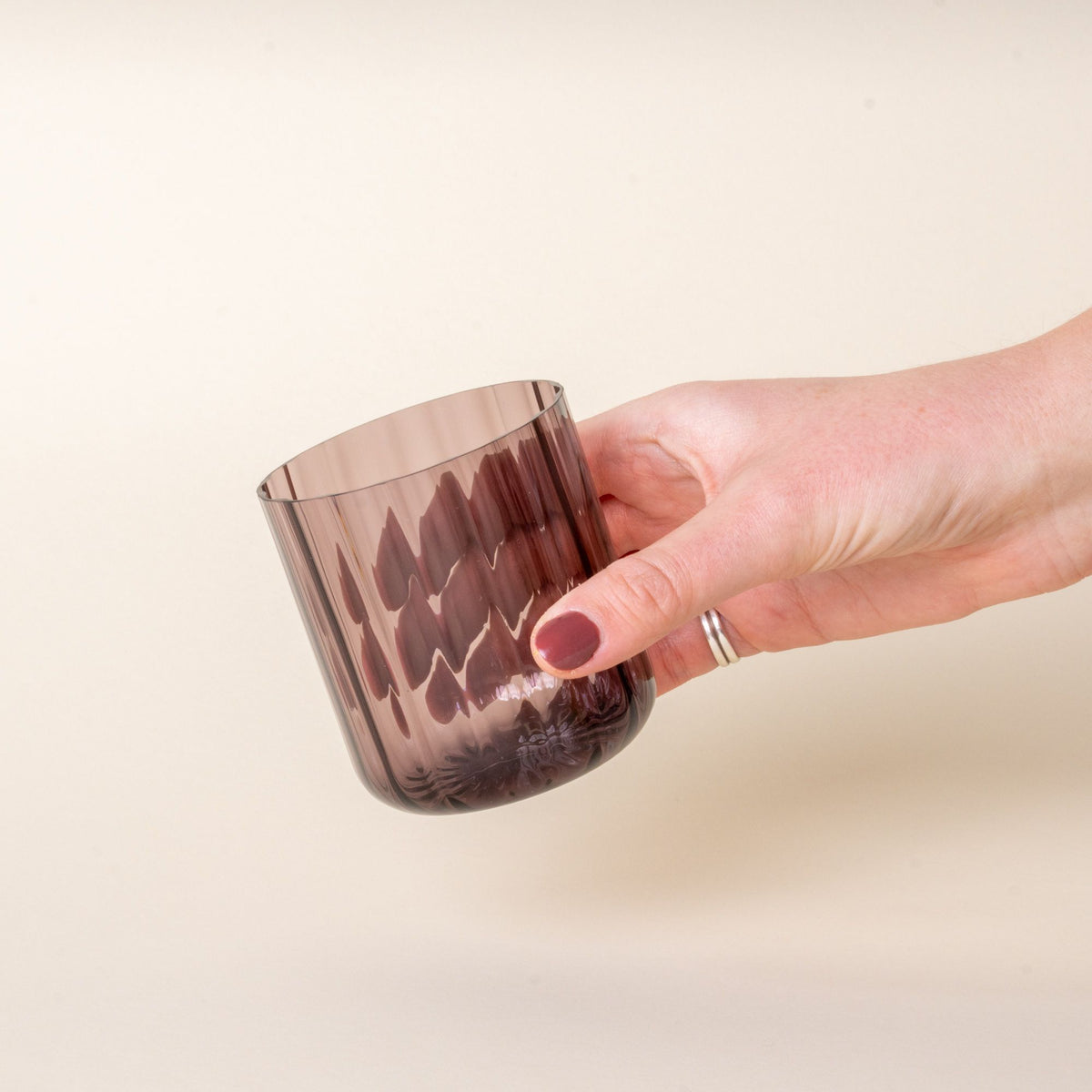 A hand holds a fluted walled tumbler in a grey purple color