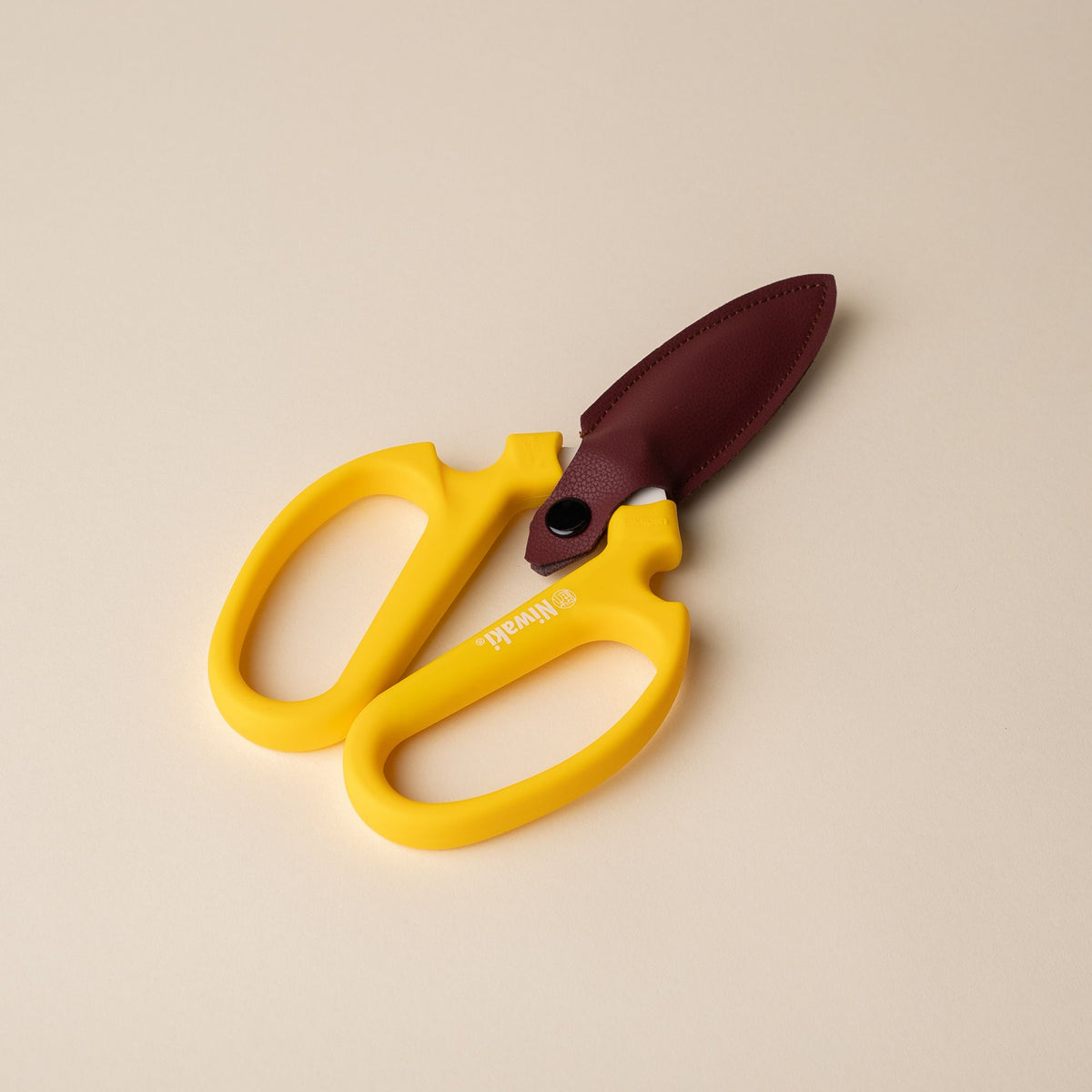 A pair of flower scissors with large yellow handles and a leather cover around the blades.