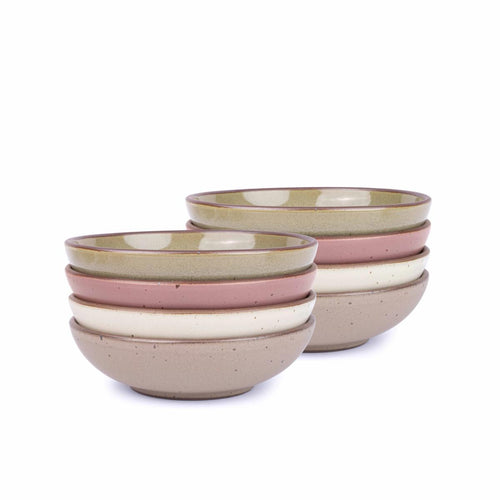 A stack of 8 dinner-sized shallow ceramic bowls in a reflective dappled grey-green, warm off-white, warm pale brown and dusty mauve pink colors featuring iron speckles and an unglazed rim