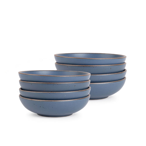 A stack of 8 dinner-sized shallow ceramic bowls in a cool, medium blue color featuring iron speckles and an unglazed rim