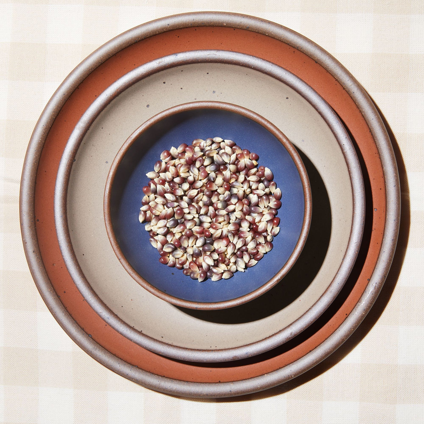 Purple and white popcorn kernels in a blue bowl on a stack of plates