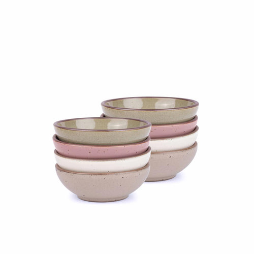 A stack of 8 small shallow ceramic bowls in a reflective dappled grey-green, warm off-white, warm pale brown and dusty mauve pink colors featuring iron speckles and an unglazed rim