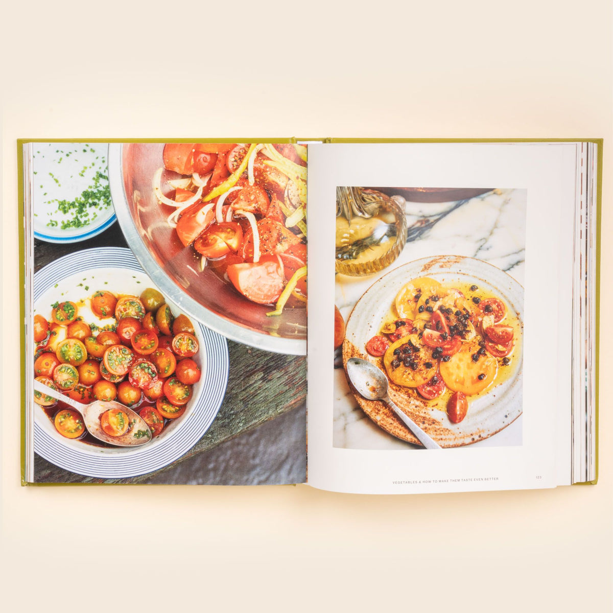 Open cookbook spread featuring vibrant tomato salads in bowls and a plated tomato dish with herbs and dressing.