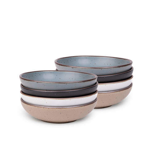 A stack of 8 dinner-sized shallow ceramic bowls in a blue-grey, graphite black, cool white, and pale warm brown colors featuring iron speckles and an unglazed rim