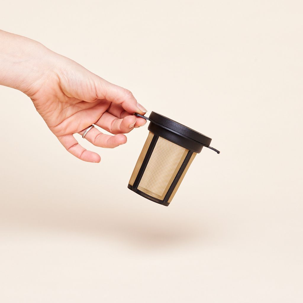 A black plastic and brown metal receptacle with black lid held by a hand